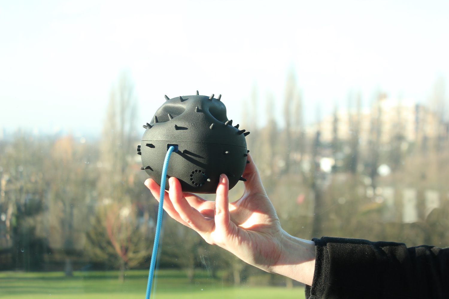 A pollen Dustbox 2.0 held up by a hand overlooking London from the Horniman museum